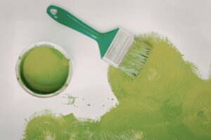 Green pain on the ground with a paint can and paint brush.