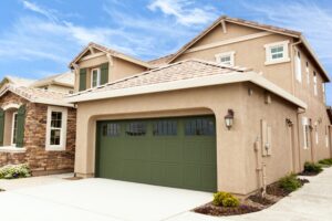 Freshly painted tan home with green garage door and accents.